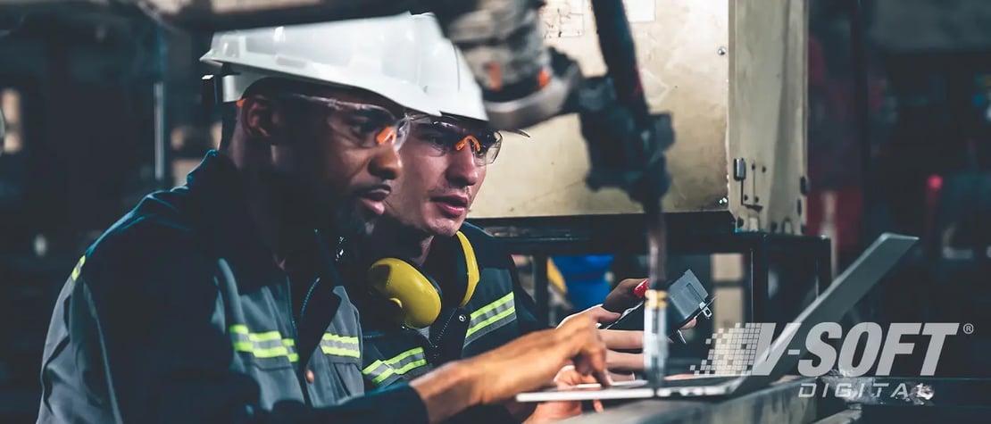 Two IoT professionals working on a manufacturing robitic arm, setting up IoT sensors.