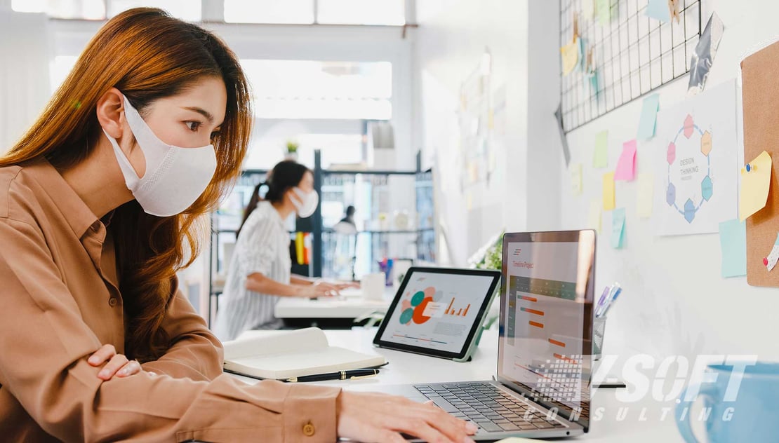 Women working at desks in office while wearing masks